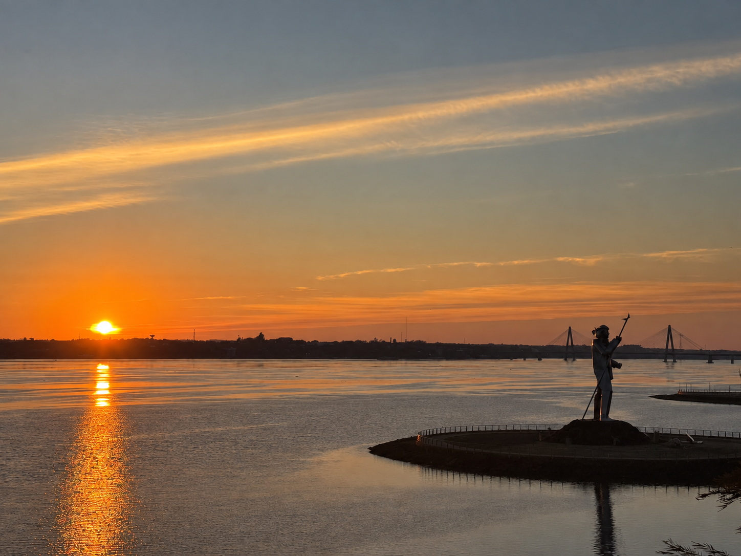 Monumento a Andrés Guacurarí y puente internacional junto al río Paraná al atardecer